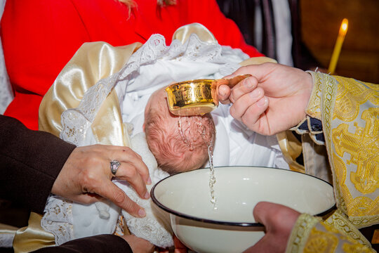 Christian baptism ceremony of a newborn baby in church. Priest pouring holy water during traditional religious ritual while family holds the infant. Sacred православ baptism moment and spiritual famil