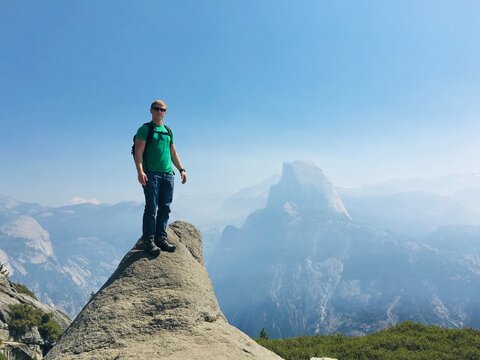 Male hiker standing on a rocky overlook, Glacier Point, Half Dome, Yosemite National Park, California, USA