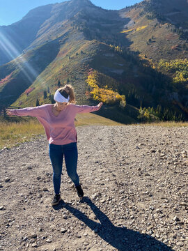 Carefree young woman in jeans and a headband spinning around in a rural landscape, Sundance, Utah, USA