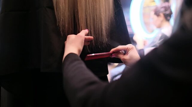 Professional hairstylist holding scissors and a comb preparing to cut long straight hair in a modern salon