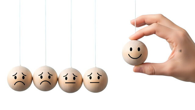 Hand holding happy face wooden ball influencing sad and neutral pendulum balls