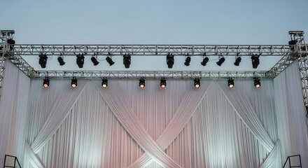 Fototapeta premium A large outdoor concert stage with multiple speakers and lights set up against a cloudy sky, ready for a performance.