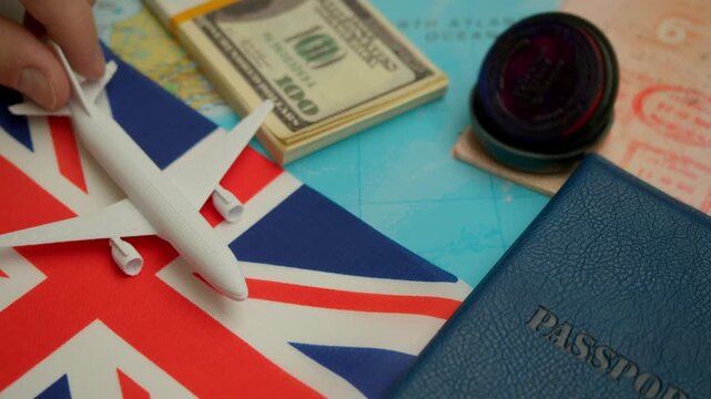 Travel concept with airplane, stamped passport, and dollar notes over world map showing United Kingdom flag, symbol of tourism to London.