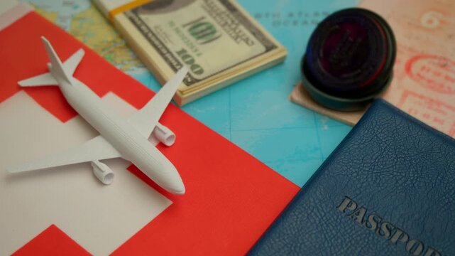 Travel concept with airplane, stamped passport, and dollar notes over world map showing Switzerland flag, symbol of European tourism and business trips.