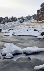 Płynąca rzeka z nurtem między zaśnieżonymi skałami © Asnyko