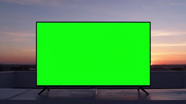 Professional video camera on tripod in a green screen studio with softbox lighting.