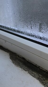 window in apartment inside is covered with water droplets due to high condensation. vertical video. drops and fogged glass. slight build-up of water. wet window glass. sill collapses from moisture.