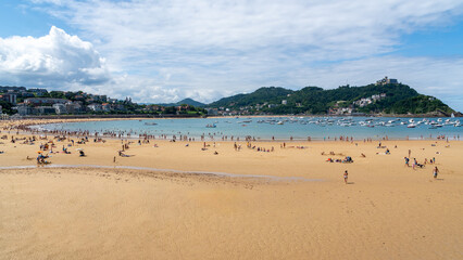 View of La Concha Beach with Santa Clara Island and Monte Igueldo in San Sebastian, Basque Country, Spain. Famous urban beach with boats and summer atmosphere.