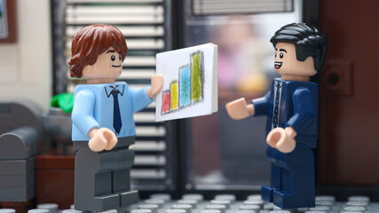 Fototapeta premium Tambov, Russian Federation - March 10, 2026 Happy Lego businessperson minifigures discussing graphs showing the results of their successful teamwork.