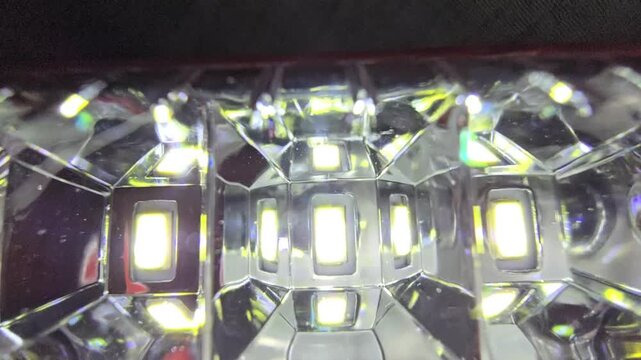 Macro video of a bright white LED array with diamond-shaped reflectors. Features a high-intensity light flare, showcasing futuristic electronic hardware and pure illumination.