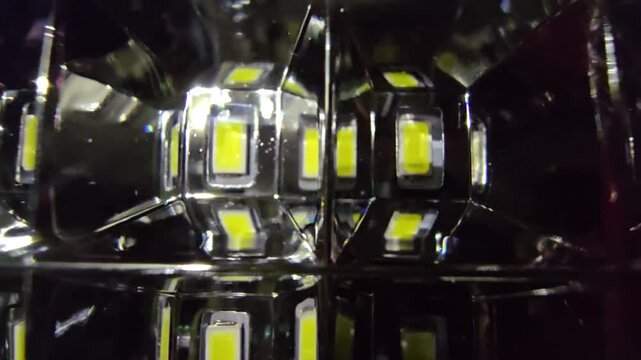 Macro shot of a futuristic LED panel. Features glowing yellow diodes reflected in a dark geometric chrome grid, creating a deep infinity effect for high-tech background use.