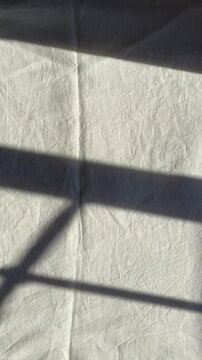 sunlight and window shadows on white linen bed sheets