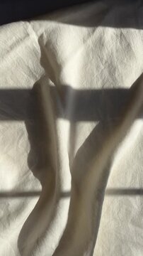 sunlight and window shadows on white linen bed sheets