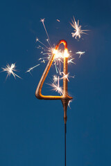 4 years celebration festive background with copy space made with Bengal fire in the form of number Four. Vertical photography.