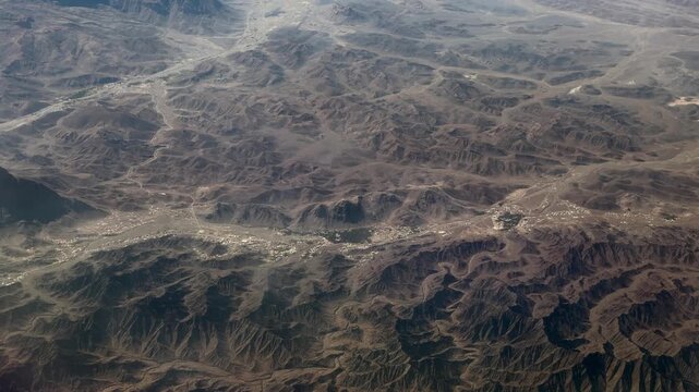 flying across landscape in northeastern part of Sultanate of Oman with desert, dried riverbeds and mountain landscape all around, small settlements are located in the valleys - 4k aerial video footage