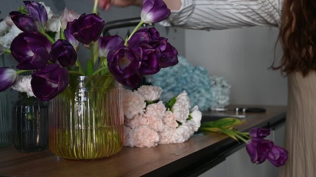 Woman trimming fresh flowers with scissors on kitchen table
