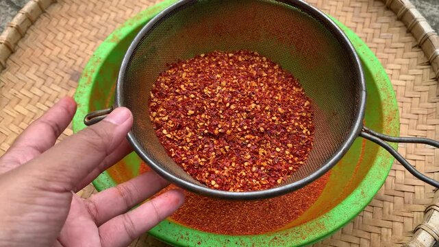 sifting dried hot peppers with strainer traditionally.