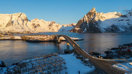 Scenic bridge over fjord with snow-covered mountains and coastal village at sunrise in Lofoten Islands, Norway © Andrei Tomas
