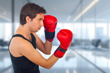 Young man stands ready in red boxing gloves