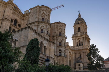Fototapeta premium Tall buildings in Malaga, Spain showcase history and architecture during early evening hours with a clear sky and construction nearby