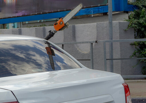 A long chain saw sticks out of a car window &mdash; too big to fit inside! The scene looks epic and slightly absurd. A white sedan drives through the city, carrying its oversized tool with style. A quirky, 