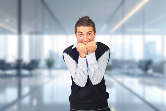 A man in a vest is shaking his hands in a room with a lot of windows