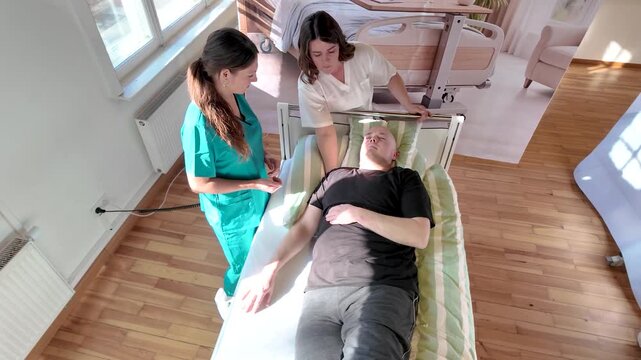 Top view of nursing instructor guiding student nurse during 30 degree positioning for pressure ulcer prevention and patient mobility