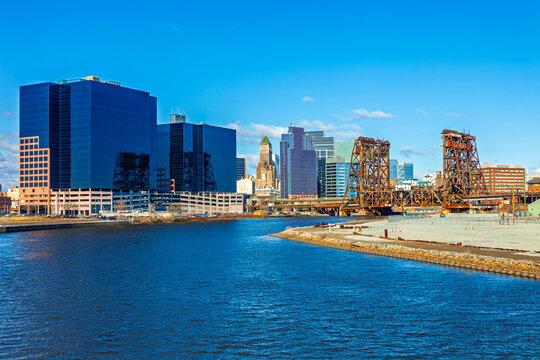 Newark, New Jersey skyline featuring the historic rusted vertical-lift bridge over the Passaic River with modern downtown skyscrapers under a blue sky.