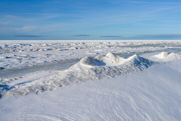 Snow Covered Baltic Sea Coast with Frozen Ice Ridges Under Clear Winter Sky © Zigmunds