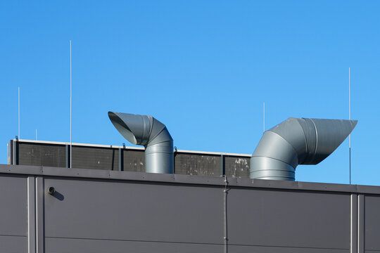 Industrial Ventilation Pipes, Air Exhaust Ducts and lightning rods on Factory Roof Under Blue Sky