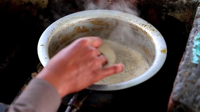 Slow Motion Shot of Hand stirring spiced tea in a metal pot with rising steam, creating a warm and inviting atmosphere at 180 fps High quality footage