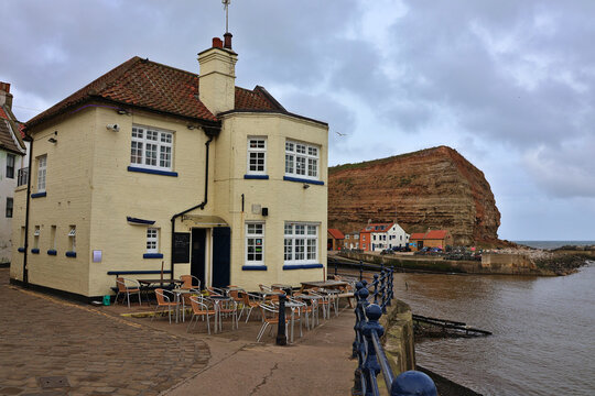 Staithes village harbour view toward Staithes Beck and Cowbar Nab, North Yorkshire Coast; historic fishing village with Cod and Lobster Pub beside coastal harbour landscape on North Sea, England, UK