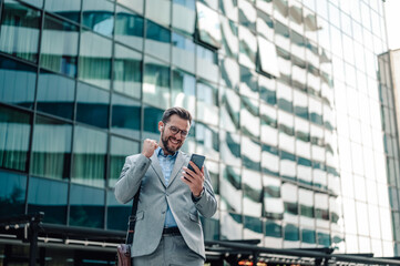 Happy businessman celebrating success checking phone notification