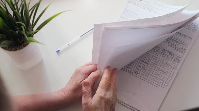 An unrecognizable business woman sorting through documents and contracts in an office