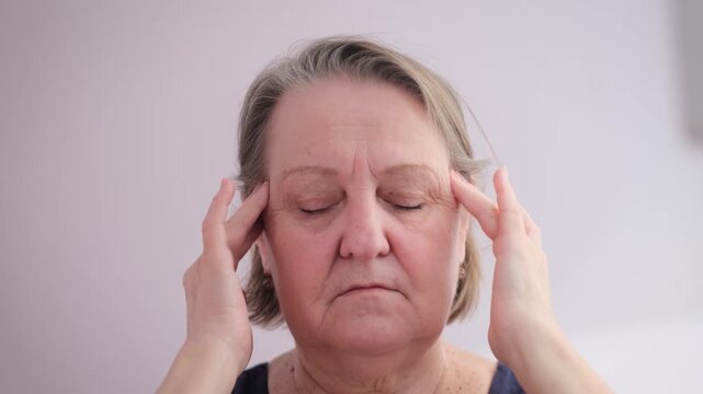 Elderly woman with headache on isolated background, close-up