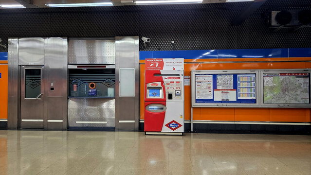MADRID, SPAIN - FEBRUARY, 17, 2026. Madrid metro ticket hall with orange wall panels vending machine and metallic elevator doors for transport background and urban design