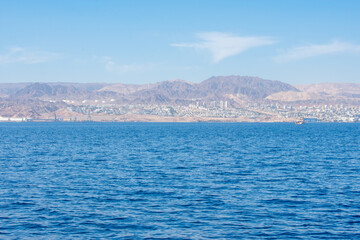 Fototapeta premium View from Aqaba in Jordan on Aqaba Gulf and Eliat In Israel. Israeli flag on Coast of Red Sea 