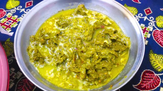 Saag dish cooked in a bowl with rich sauce resting on a colorful tablecloth 4k Footage