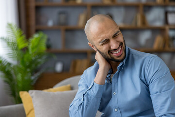 Man feeling sharp pain in his neck, rubbing it with his hand while grimacing, indicating muscle...