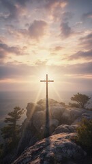 Obraz premium Vertical photo of wooden cross on rocky mountain peak at sunset. Christian religious symbol with sun rays and dramatic sky. Easter resurrection concept