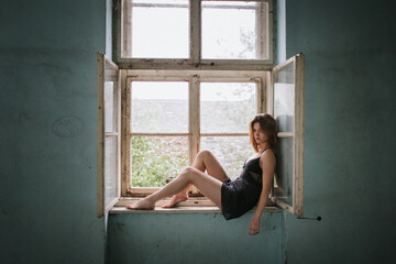 Woman Sitting in Open Window of Abandoned Building