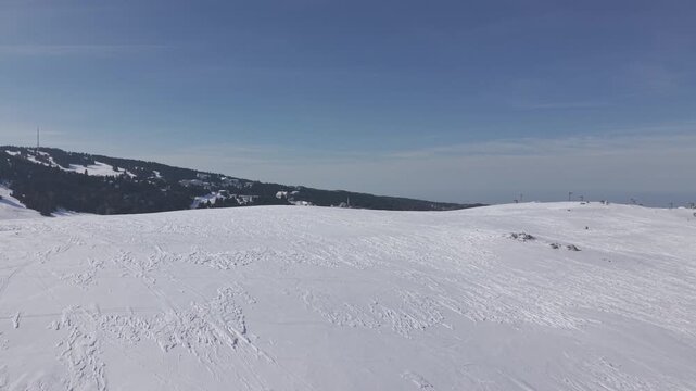 Aerial forward tracking shot approaching the ski resort facilities, ski lifts, and snowy slopes at Uludag