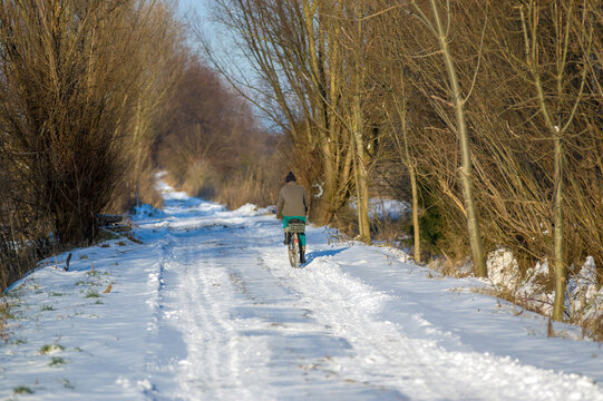  Rowerzysta jadący zasypaną śniegiem drogą.