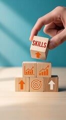 A hand placing a wooden block with the word skills on top of a stack of blocks with various business and growth icons