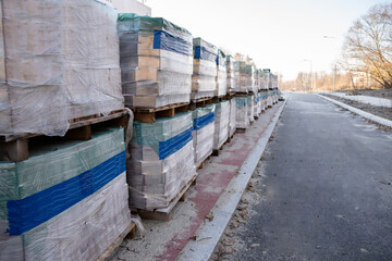 Obraz premium Stacks of packaged building materials on pallets at a construction site