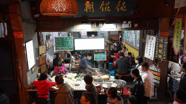 Crowded traditional copper pot stew restaurant in Jinli Alley Chengdu at night with steaming dishes and diners