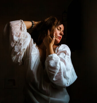 Woman in white blouse with her hands by her face