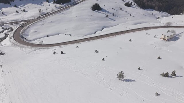 Aerial forward tracking shot over a snow-covered ski resort and mountain road at Uludag
