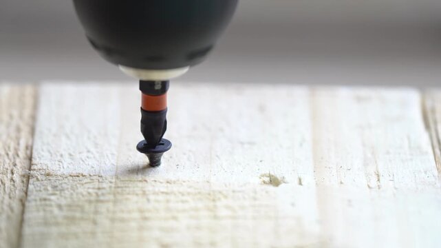 Screwing a screw into a wooden surface with an electric screwdriver, close-up, ASMR sound

