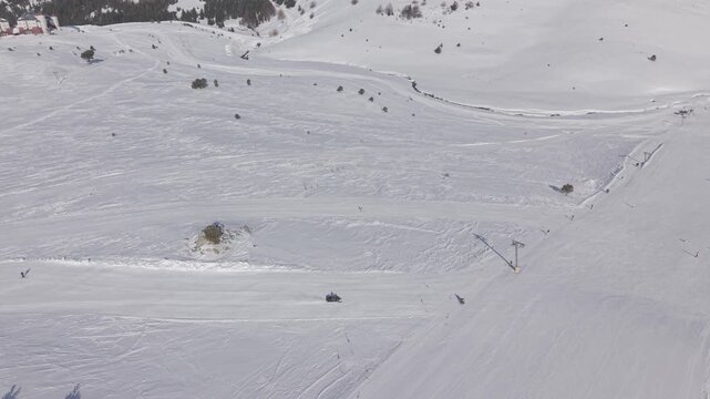 Aerial tracking shot circling right around a fast snowmobile riding across a snowy winter landscape